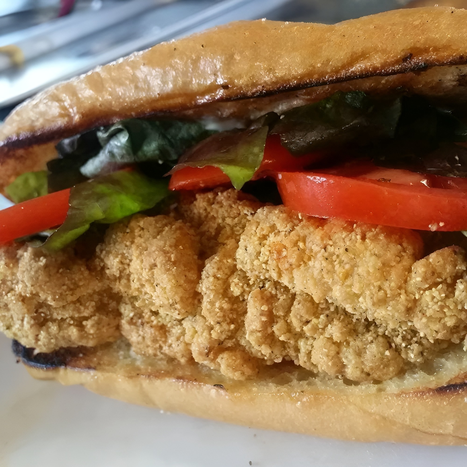 Close-up of a Big Easy Bistro fried shrimp po'boy with lettuce and tomatoes on a toasted bun.