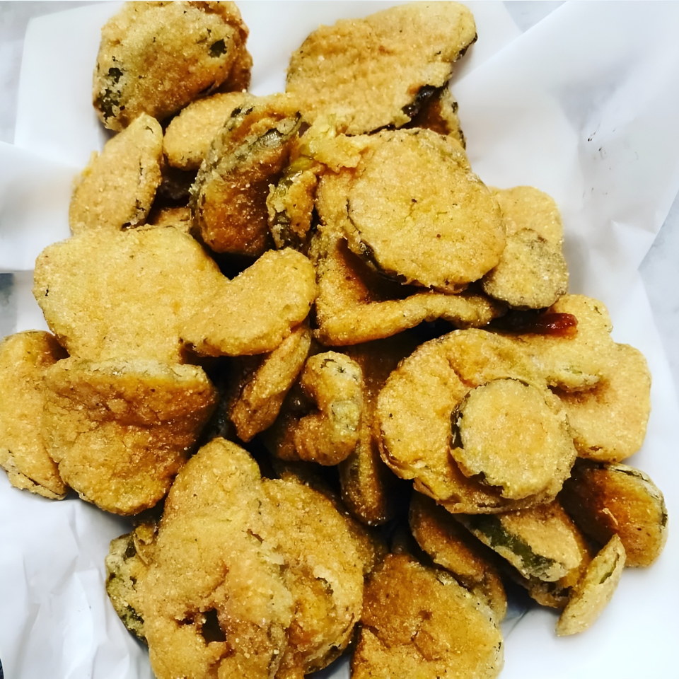 Close-up of a pile of golden-brown fried pickles, a popular American appetizer.