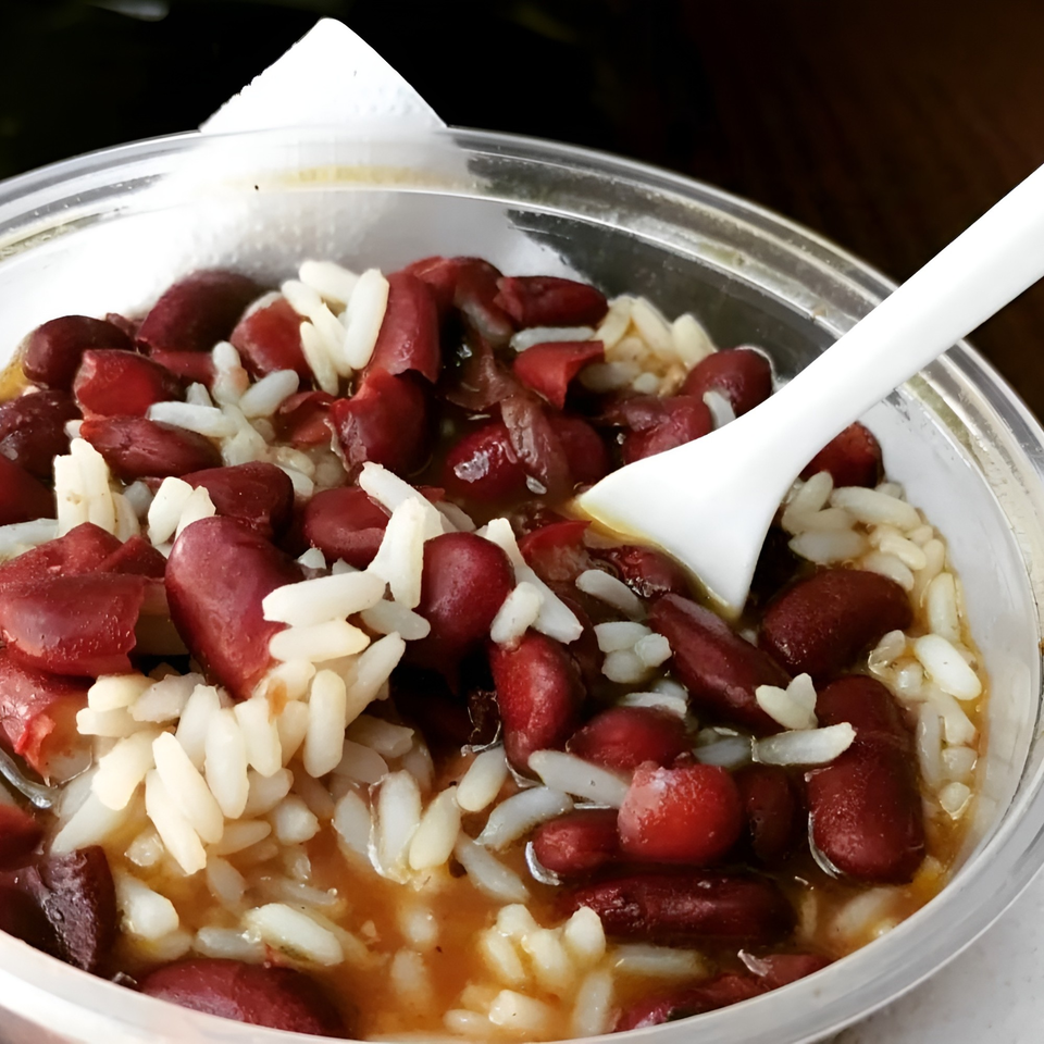 Close-up of Big Easy Bistro's red beans and rice in a clear plastic container with a white spoon.
